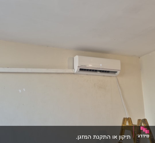 מזגן מותקן על קיר עם סולם לידו